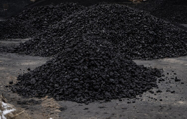 Piles of coal on sale at coal yard or depot. Heap of coal at warehouse. Solid fuel energy resource.