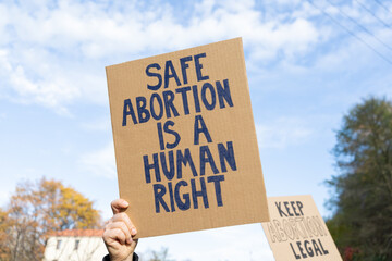 Protesters holding signs with slogans Safe abortion is a human right and Keep abortion legal. People with placards supporting abortion at protest rally demonstration. - obrazy, fototapety, plakaty