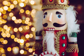 Christmas nutcracker wooden figure. Beautiful, festive toy soldier decoration, with Christmas tree lights bokeh in background.
