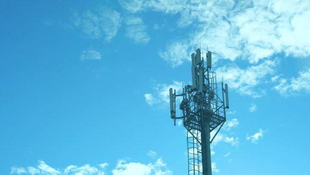 Close-up Cellular Tower 5G 4G 3G, Mobile Operator Station Communications Network and Time Lapse Blue Sunny Sky and White Clouds.