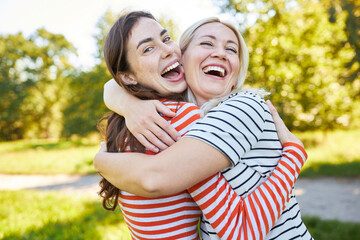 Zwei lachende Freundinnen umarmen sich in Natur - obrazy, fototapety, plakaty