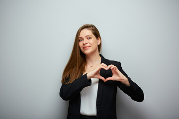 Smiling business woman in black suit holding heart figure with fingers, isolated portrait.