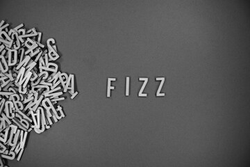pile of wooden English language capital letters spilling into words - FIZZ in black and white