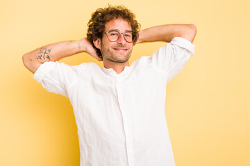 Young smart caucasian man on yellow background stretching arms, relaxed position.