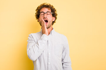 Young smart caucasian man on yellow background yawning showing a tired gesture covering mouth with hand.