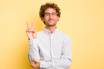 Young smart caucasian man on yellow background showing number two with fingers.