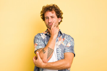 Young smart caucasian man on yellow background unhappy looking in camera with sarcastic expression.
