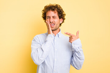 Young smart caucasian man on yellow background having a strong teeth pain, molar ache.