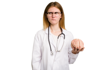 Young doctor caucasian woman holding a brain isolated confused, feels doubtful and unsure.