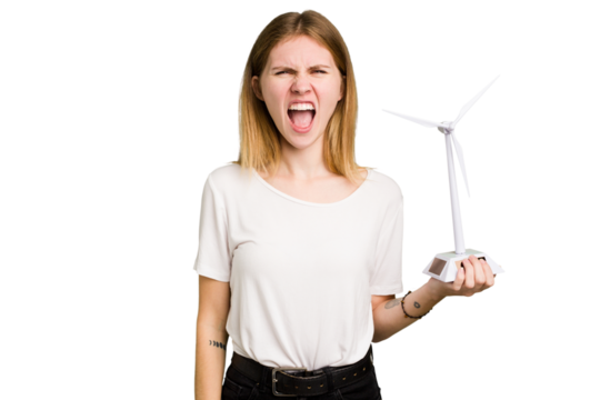 Young caucasian woman holding a small wind energy mill isolated screaming very angry and aggressive.