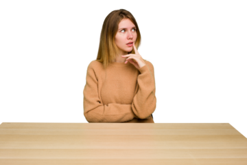 Young caucasian woman sitting on a chair in a desktop isolated contemplating, planning a strategy, thinking about the way of a business.