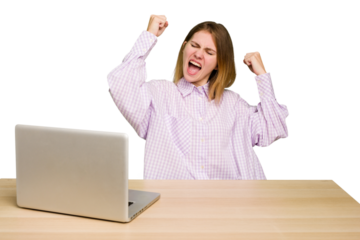 Young caucasian woman in a workplace working with a laptop isolated raising fist after a victory, winner concept.