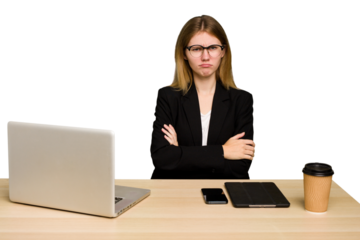 Young business caucasian woman working on her workplace cutout isolated unhappy looking in camera with sarcastic expression.