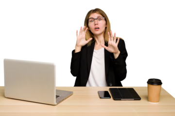 Young business caucasian woman working on her workplace cutout isolated being shocked due to an imminent danger