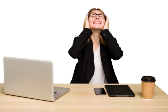 Young business caucasian woman working on her workplace cutout isolated laughs joyfully keeping hands on head. Happiness concept.