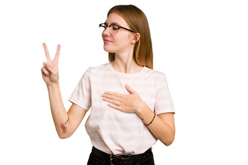 Young caucasian woman isolated taking an oath, putting hand on chest.