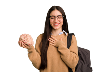 Young caucasian student woman holding a brain isolated laughs out loudly keeping hand on chest.