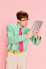 Funny emotional man, student geek wearing vintage style shirt and trousers having fun, using tablet...
