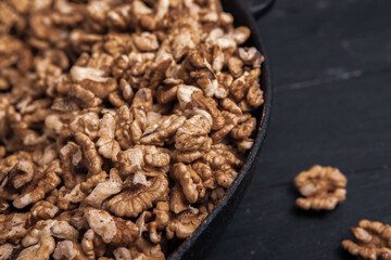 Walnut background. Peeled walnuts on a iron plate on black. walnuts a real super food full of vitamins and vegetable fats