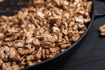 Walnut background. Peeled walnuts on a iron plate on black. walnuts a real super food full of vitamins and vegetable fats
