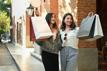Two trendy beautiful women with shopping bags walking alone city street. Shopping, tourism and...