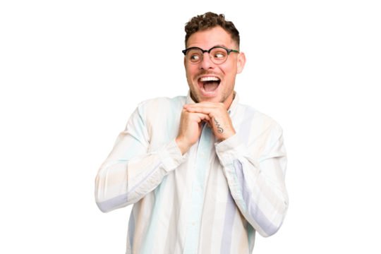 Young caucasian handsome man isolated keeps hands under chin, is looking happily aside.