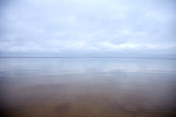 Transparent sea water surface with cloudy sky on a winter day, selective focus