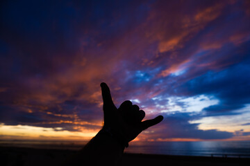 silhouette of a hang loose hand at sunset
