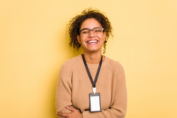 Young brazilian woman with a badge isolated on yellow background laughing and having fun.