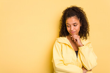 Fototapeta na wymiar Young Brazilian curly hair cute woman isolated on yellow background looking sideways with doubtful and skeptical expression.