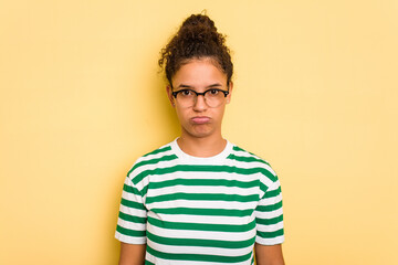 Young Brazilian curly hair cute woman isolated on yellow background sad, serious face, feeling miserable and displeased.