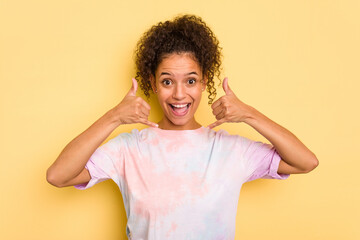 Fototapeta na wymiar Young Brazilian curly hair cute woman isolated on yellow background showing a mobile phone call gesture with fingers.
