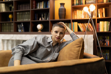 tired caucasian businesswoman after work is resting in an armchair on the background of home library