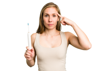 Young caucasian holding a brushing teeth isolated pointing temple with finger, thinking, focused on a task.