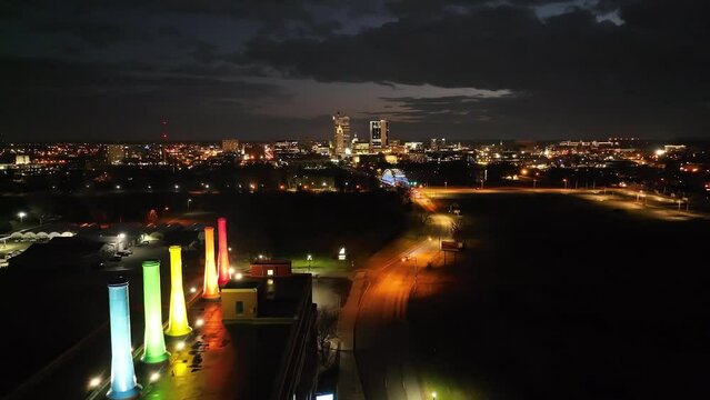 Wide shot of Fort Wayne, Indiana skyline and City Light and Power Plant at night with drone moving forward.