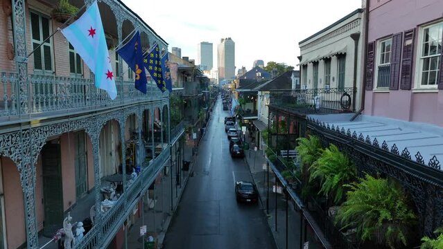 Galleries and flags adorn homes in French Quarter of New Orleans. Rising aerial reveals skyline and ferns.