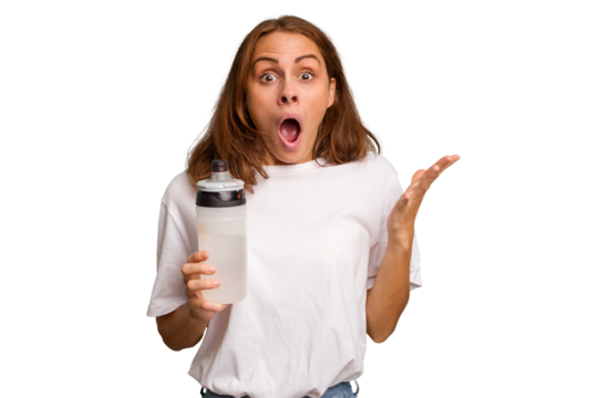 Young caucasian sport woman holding a bottle of water isolated surprised and shocked. - Powered by Adobe
