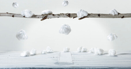 A white wooden table with snow in the balls and a natural branch with free space