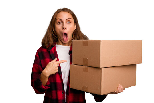 Young caucasian woman moving while picking up a box full of things isolated pointing to the side