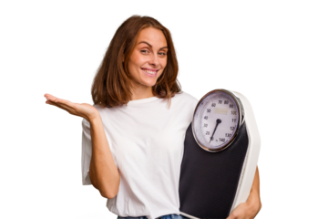 Young caucasian woman holding a scale and measure tape isolated showing a copy space on a palm and holding another hand on waist.