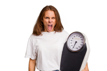 Young caucasian woman holding a scale and measure tape isolated screaming very angry and aggressive.