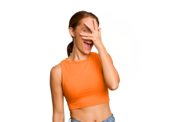 Young caucasian woman isolated blink at the camera through fingers, embarrassed covering face.