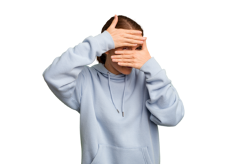 Young caucasian woman isolated blink at the camera through fingers, embarrassed covering face.