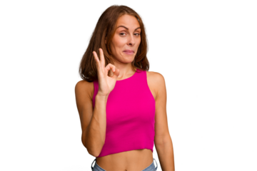 Young caucasian woman isolated winks an eye and holds an okay gesture with hand.