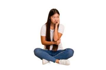 Young asian woman sitting on the floor cutout isolated who feels sad and pensive, looking at copy space.