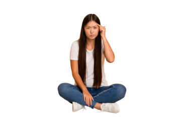 Young asian woman sitting on the floor cutout isolated pointing temple with finger, thinking, focused on a task.