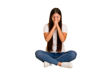 Young asian woman sitting on the floor cutout isolated holding hands in pray near mouth, feels confident.