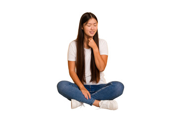 Young asian woman sitting on the floor cutout isolated suffers pain in throat due a virus or...