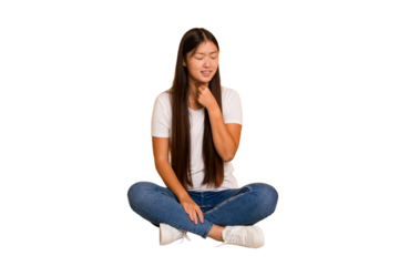 Young asian woman sitting on the floor cutout isolated suffers pain in throat due a virus or infection.