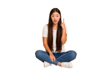 Young asian woman sitting on the floor cutout isolated having an idea, inspiration concept.